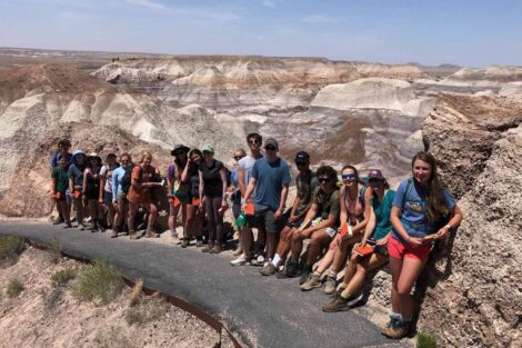 students stand on a curved road surrounded by massive rocky formations