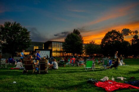 Easton community members sitting on the lawn of the Quad watching a free outdoor movie screening with Skillman Library in the background