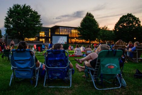 Easton community members sitting on the lawn of the Quad watching a free outdoor movie screening