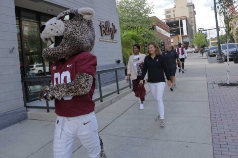 Lafayette College President Nicole Hurd, head football coach John Troxell, football team members, and Leopards mascot walking in front of Billy's restaurant in Easton