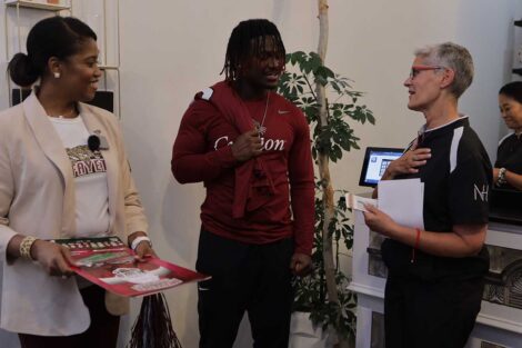 Lafayette College President Nicole Hurd, head football coach John Troxell, football team members, and Leopards mascot surprising co-owner of NuHouse in Easton with free football tickets and jerseys
