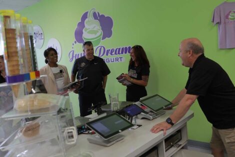 Lafayette head football coach John Troxell and Athletics Director Sherryta Freeman surprising owner of Just a Dream frozen yogurt shop with Lafayette football tickets and swag