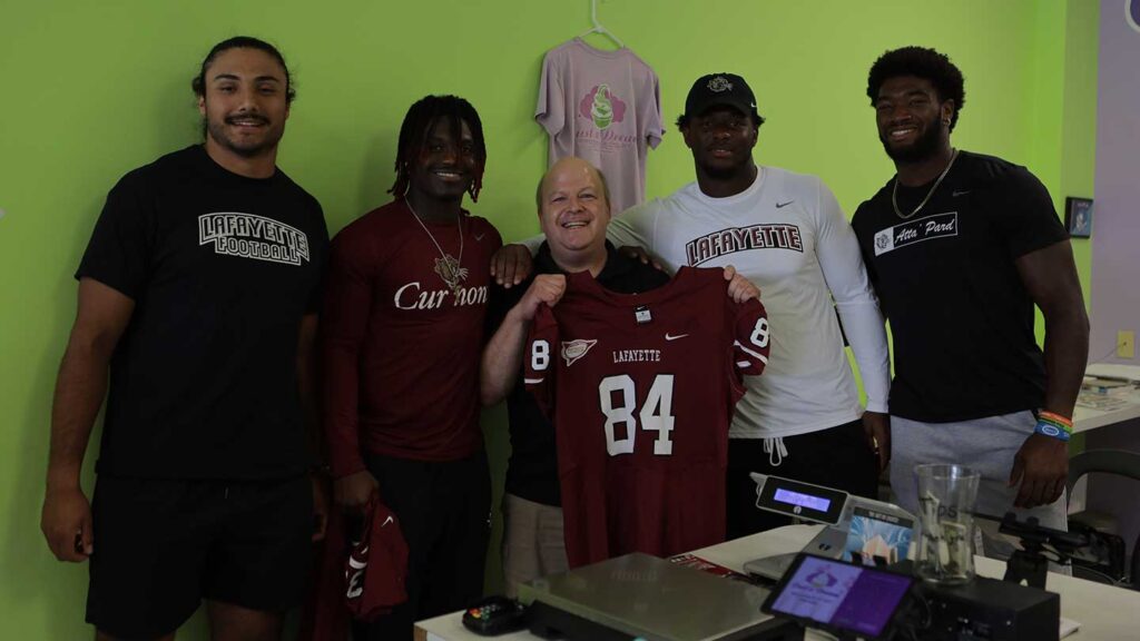Lafayette football players Marco Olivas, Malik Hamm, Nahjee Adams, and Jyaire Stevens surprising the owner of Just a Dream frozen yogurt shop with a Lafayette jersey