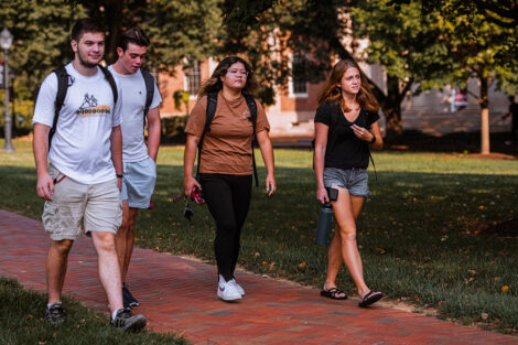 Students walk across the Quad, smiling.