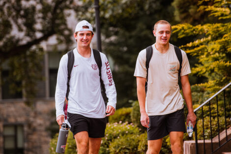 Students walk across the Quad, smiling.