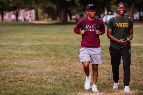 Students walk across the Quad, smiling.