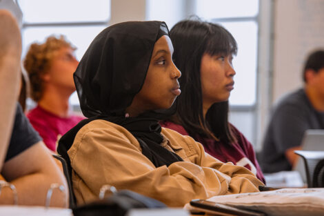 Students listen to professor in a classroom.