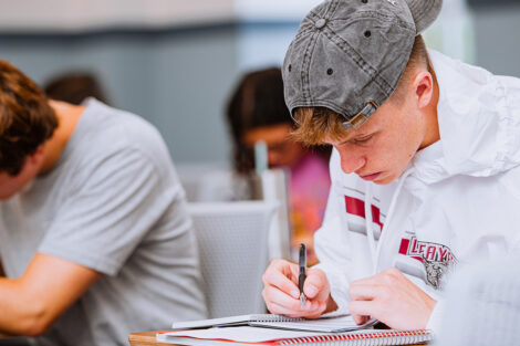 A student takes notes at a desk.