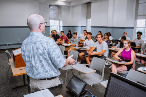 Students sit in a classroom, listening to a professor.