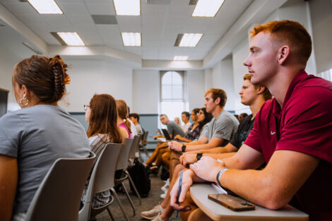 Students sit in a classroom, listening to a professor.