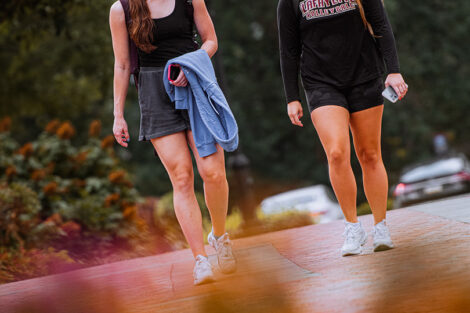 Students walk across the Quad, smiling.