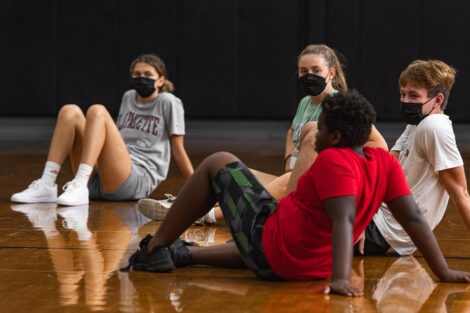 Lafayette students sit with a young Easton student on the floor of a gymnaisium