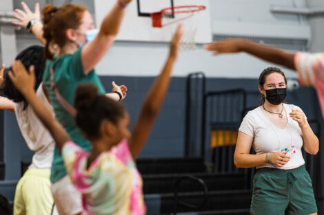 Lafayette students smile and raise their arms with young Easton students in a gymnasium