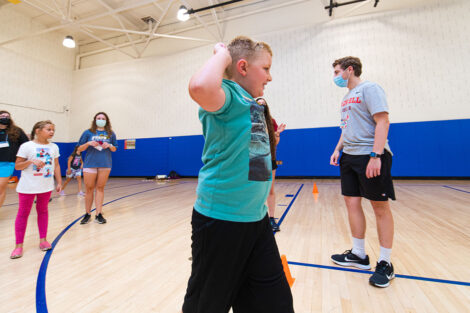 a young boy and other children run through a gymnasium