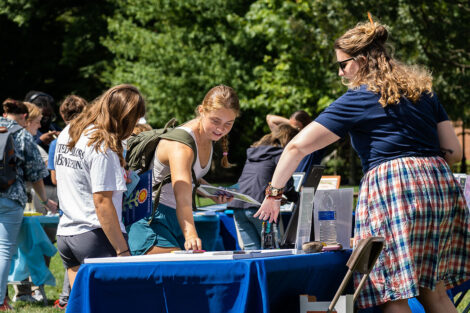 Students take pamphlets from a table outside on the Quad.