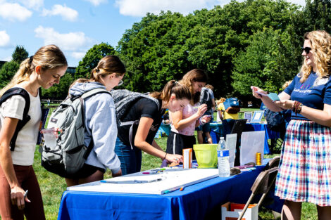 Students write at a table on the Quad.