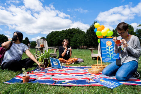 Student sit at a blanket on the Quad.