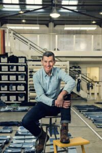 Chip Bergh is seated on a stool in an expansive office. He is wearing a light blue shirt. 
