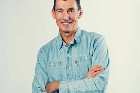 Chip Bergh is standing with his arms crossed and wearing a blue button down shirt.