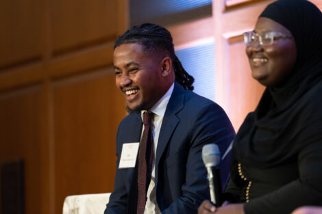 Matwos Tadesse '24 is wearing a dark jacket, dark tie and is smiling at the audience.