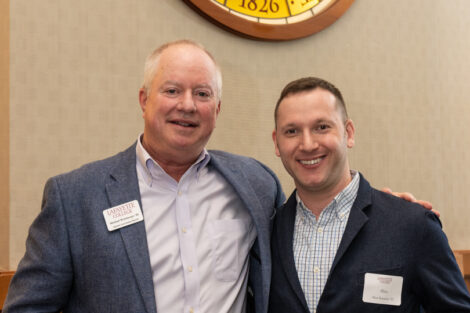 Standing under the medallion of the Marquis de Lafayette, Alumni Association Board President Michael Weisburger '82 congratulates Alan Raisman '10. Raisman is holding a gift.