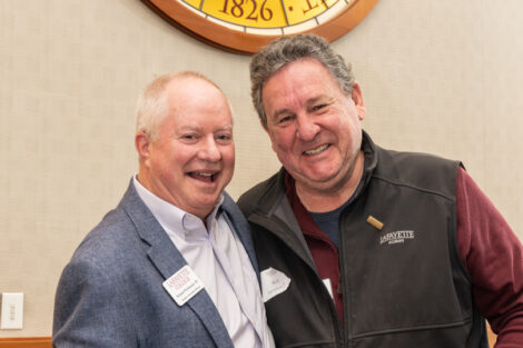 Standing under the medallion of the Marquis de Lafayette, Alumni Association Board President Michael Weisburger '82 poses with Rick Beltram '73 who is holding a leopard wrapped gift.