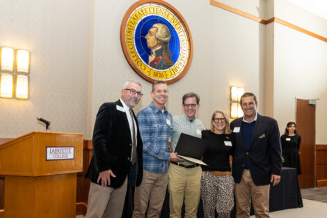 Standing under the medallion of the Marquis de Lafayette, members of the Class of 1987 pose with a certificate.