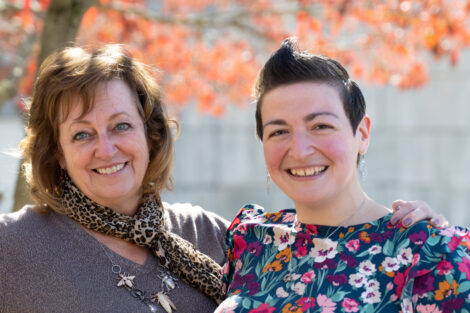 Standing outside, Professor Waters and Sara Kreisel '07 pose arm in arm. Kreisel is wearing a floral dress.