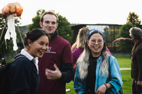 A group of students smile; a squid kite can be seen behind them